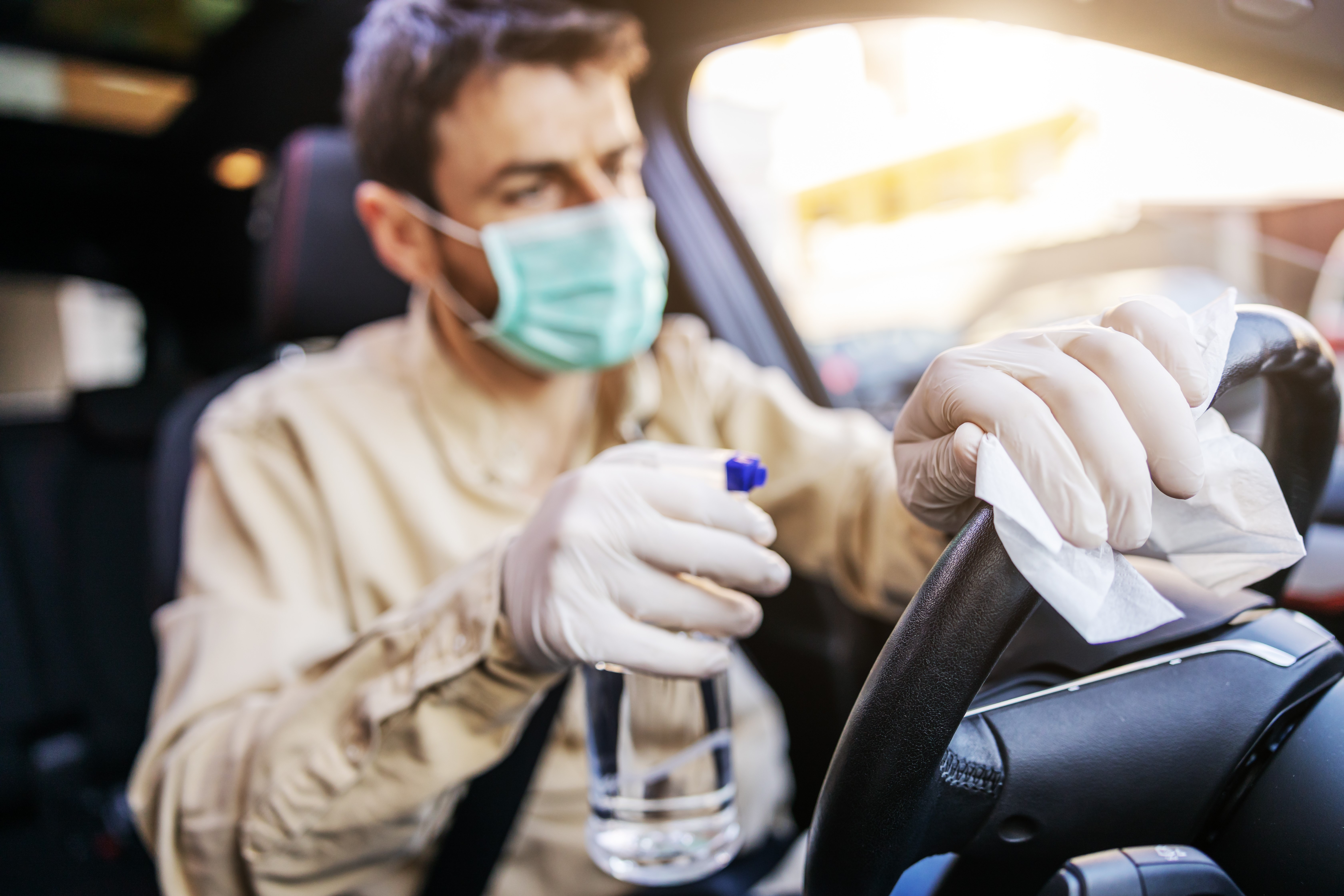 Car Wash Employee Wearing Masks and Gloves Cleaning Interior of Car